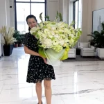 WOWBouquet Madison Avenue Whites flower arrangement held by a smiling woman