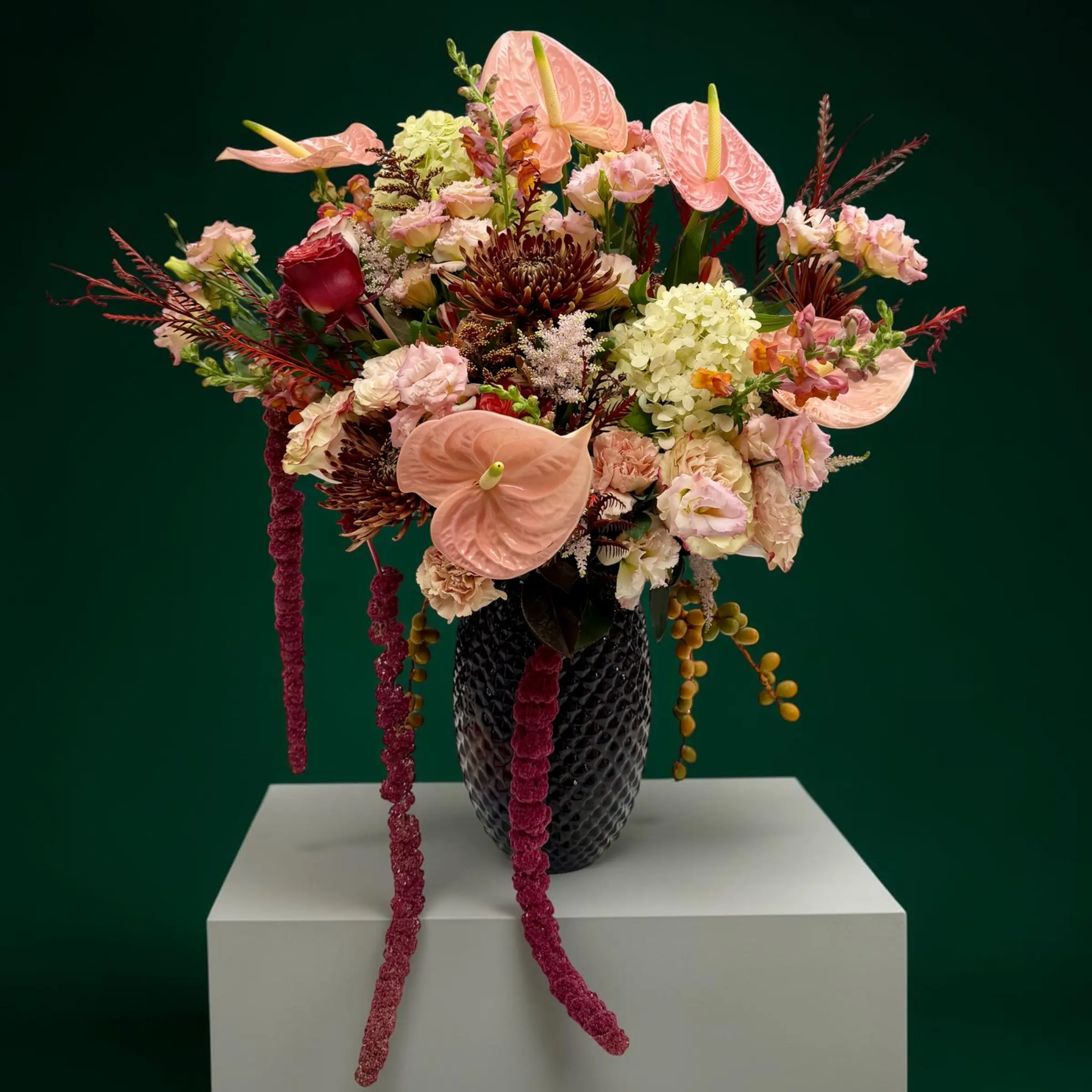 The Fifth Avenue Statement grand floral arrangement featuring pink anthuriums, premium roses, hydrangeas, and burgundy amaranthus in a black vase Grand flower arrangement with cascading burgundy amaranthus, tropical anthuriums, and premium seasonal blooms for Manhattan flower delivery