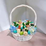 Assorted sweets and a bouquet of flowers in a baby-themed gift basket