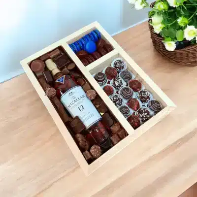 A delightful assortment of sweets, including macarons, chocolate-dipped strawberries, nuts, and chocolates, beautifully arranged in a wooden box