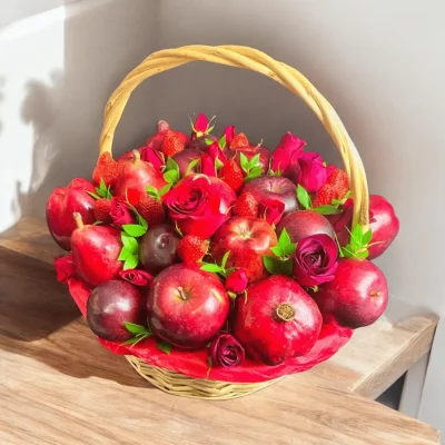 Assorted fruit gift basket with apples, plums, strawberries, pears, pomegranate, and vibrant red roses for a special occasion.