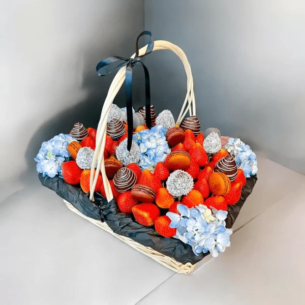 Fresh strawberries, chocolate covered strawberries, macaroons, and blue hydrangeas arranged in an elegant gift basket