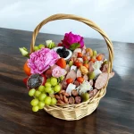 Gourmet gift basket with pomegranates, figs, strawberries, and cheeses