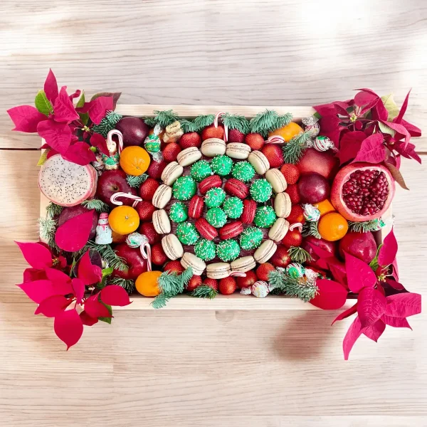 Spread holiday cheer with a Christmas gift box filled with fresh fruits, macarons, flowers, and chocolate strawberries.