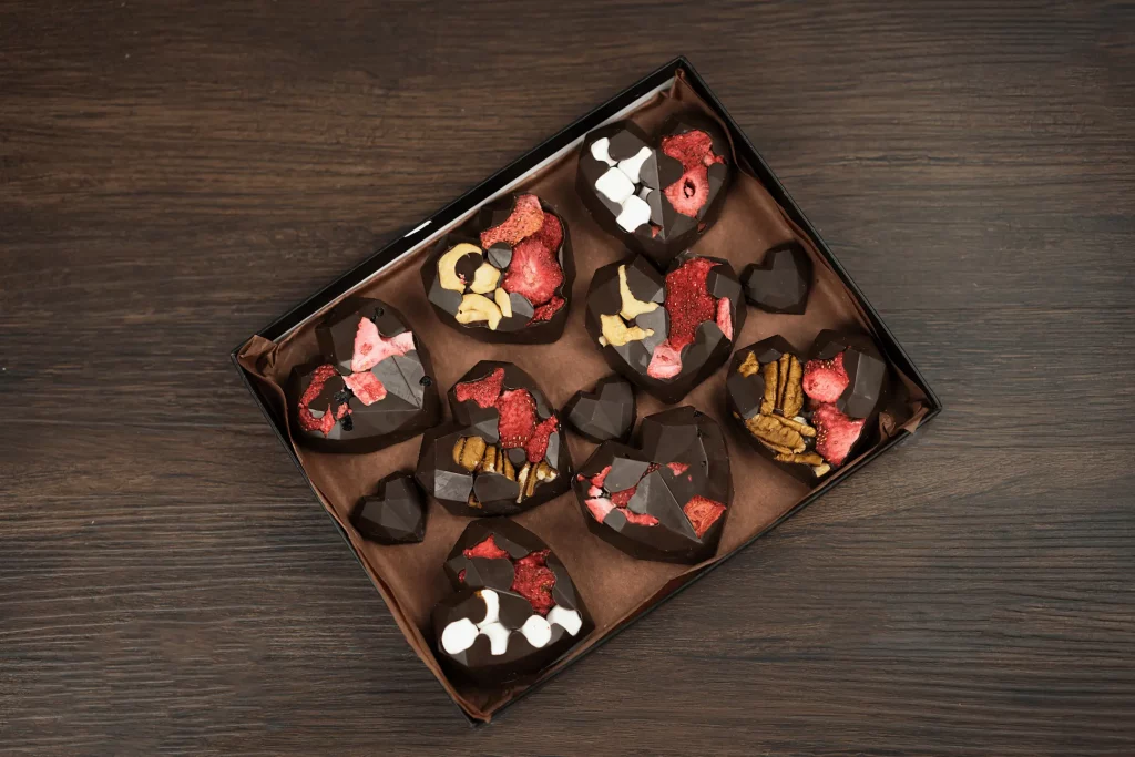 Custom-made chocolate hearts in a gift box, offering a mix of crunchy nuts, soft marshmallows, and tart strawberries, perfect for Valentine's Day or as a loving gesture.