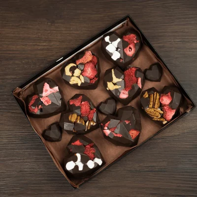 Custom-made chocolate hearts in a gift box, offering a mix of crunchy nuts, soft marshmallows, and tart strawberries, perfect for Valentine's Day or as a loving gesture.