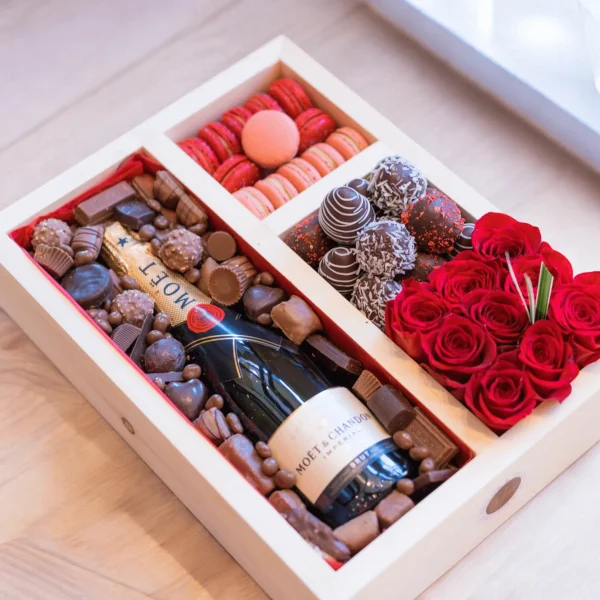 Beautifully crafted gift box including macaroons, chocolates, and a stunning rose arrangement