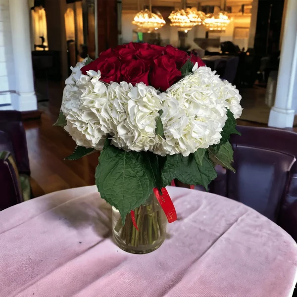 Picture of a popular NYC floral arrangement, featuring a harmonious mix of hydrangeas and roses, elegantly displayed in a tall glass vase.