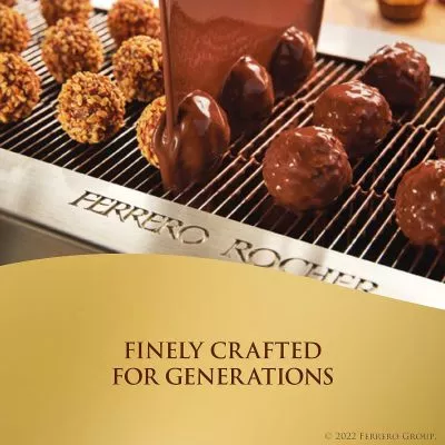 Close-up of a Ferrero Rocher, showcasing its golden wrapper, hazelnut center, and layers of chocolate and wafer.