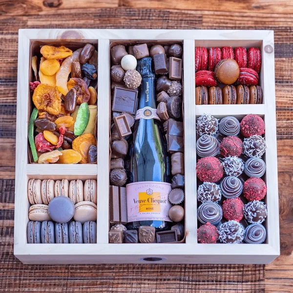 An elegantly designed holiday gift box featuring a selection of nuts, dried fruits, and a bottle of liquor.