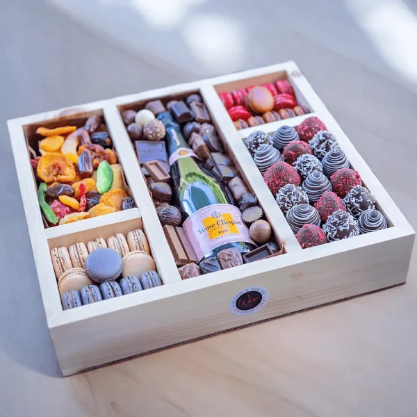 An elegantly designed holiday gift box featuring a selection of nuts, dried fruits, and a bottle of liquor.