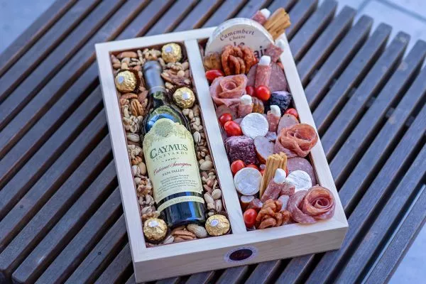 Custom wooden box filled with gourmet nuts, meats, and cheeses.