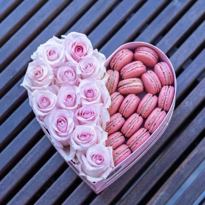 Heart-shaped box showcasing vibrant roses and gourmet macarons.