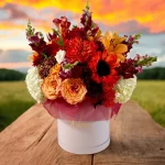 A rustic arrangement of fall flowers, showcasing yellow sunflowers, orange lilies, and red dahlias