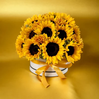 Picture of a sunflower-filled hatbox sitting on a table, highlighting the dense and cheerful arrangement of yellow blooms