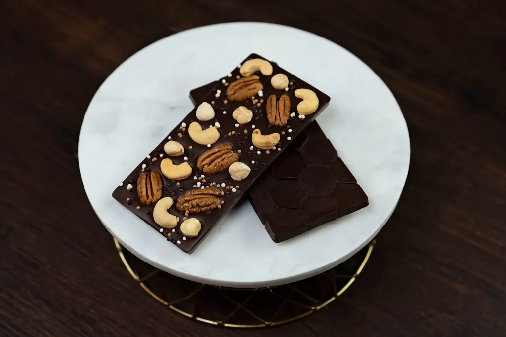 Delicious Nuts Dark Chocolate Bar featuring a rich blend of dark chocolate with whole pecans, hazelnuts, and cashews, showcasing a perfect harmony of smooth, deep chocolate and crunchy, nutty accents