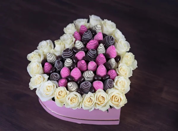 Showcasing a romantic heart-shaped arrangement made of vibrant roses and chocolate-covered strawberries, symbolizing love and sweetness.