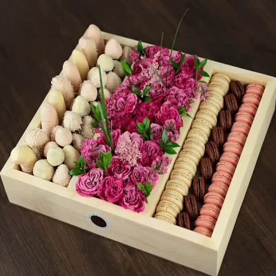 On the left, savor the decadence of Chocolate Covered Strawberries and Chocolate Covered Bananas, a classic and irresistible combination. In the center, the box showcases beautiful flowers, adding a touch of natural beauty and fragrance. On the right, discover a variety of exquisite macarons, each a burst of flavor and color.
