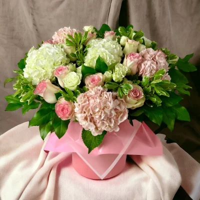 Overhead shot of a luxury floral arrangement in a hat box, combining pink roses with pink and white hydrangeas, designed for a chic presentation.