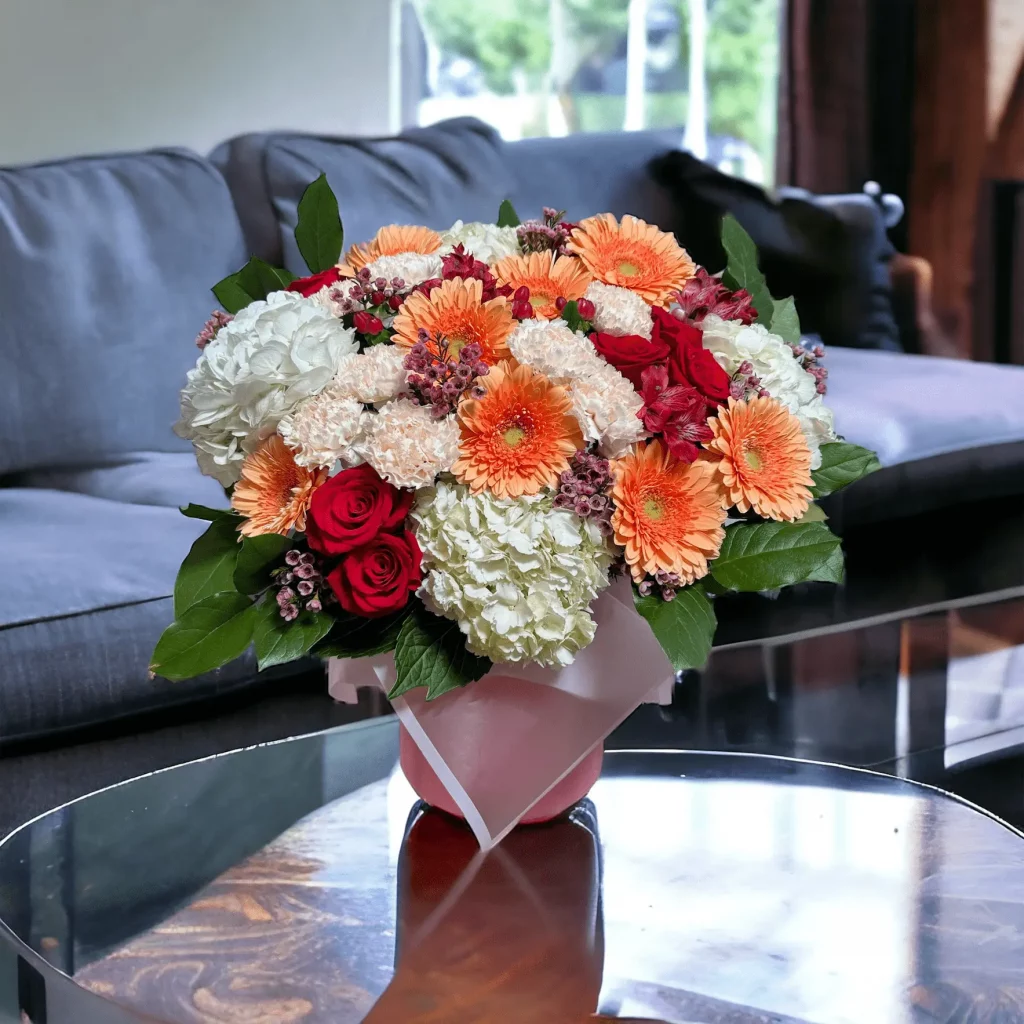 Overhead shot of a seasonal spring floral arrangement, displaying a carefully selected mix of hydrangeas, roses, and bright gerbera daisies.