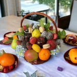 A detailed image of a premium fruit basket, displaying an array of fruits like dragonfruit and mangos, complemented by exquisite macarons and a striking hydrangea.