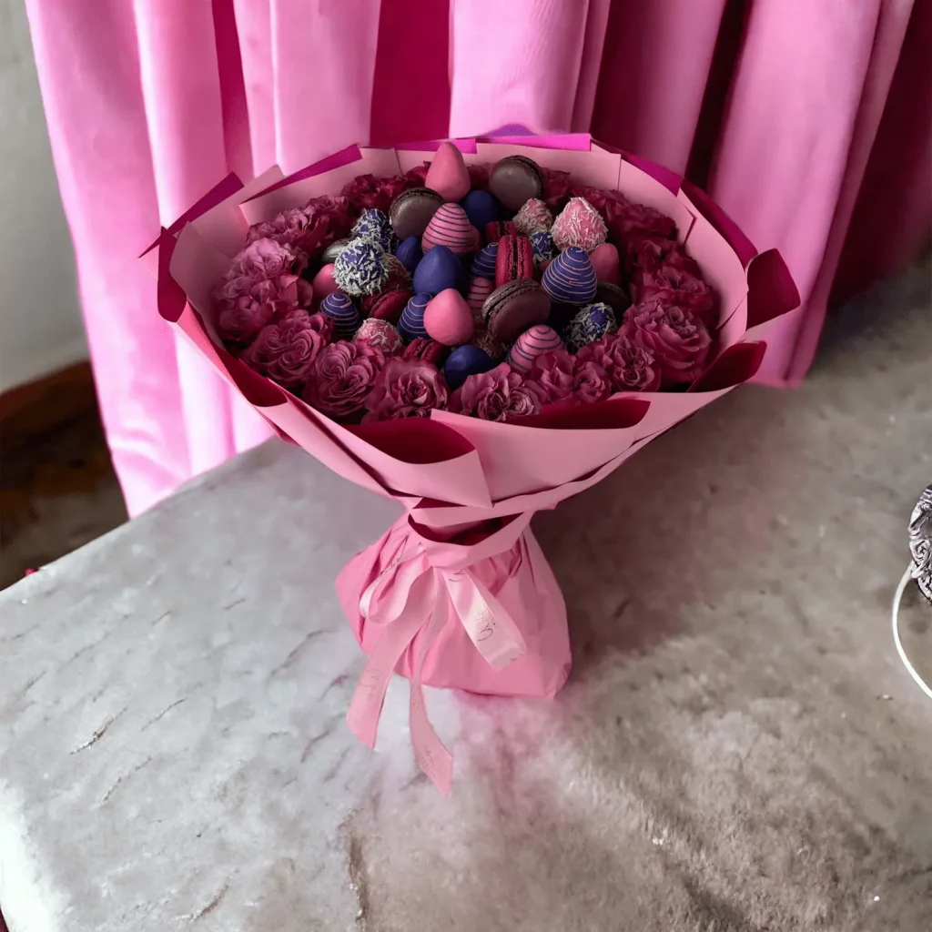 A vibrant bouquet of hot pink roses interspersed with chocolate-covered strawberries, tied together with a silky white ribbon.