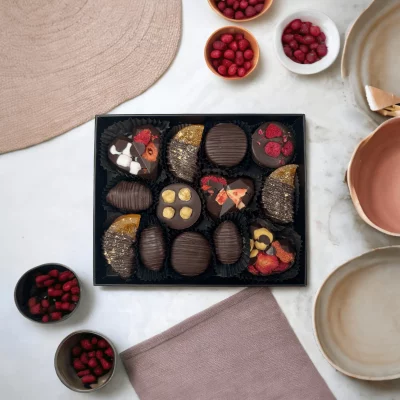 Festive setting showing the gift box of chocolate treats amidst celebration decorations.