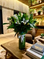 Serene arrangement of white lilies and green foliage in a vase.