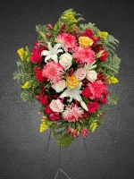 Side angle of white lilies and red flowers in a standing spray.