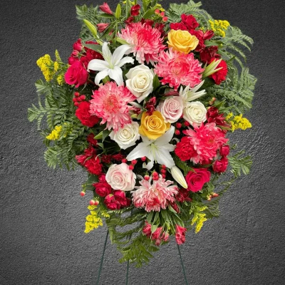 Side angle of white lilies and red flowers in a standing spray.