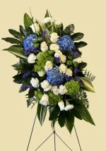 Lush greenery complementing white flowers in a funeral arrangement.