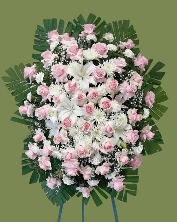 Funeral spray featuring lush pink and white flowers with greenery.