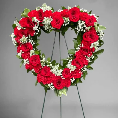 Side angle showing the lush greenery and red flowers in a heart spray.