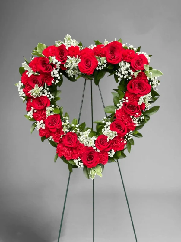 Side angle showing the lush greenery and red flowers in a heart spray.