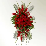 Detailed look at red carnations and gladiolus in a funeral arrangement.