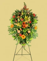 Funeral spray with bright orange lilies, roses, and greenery for memorials.