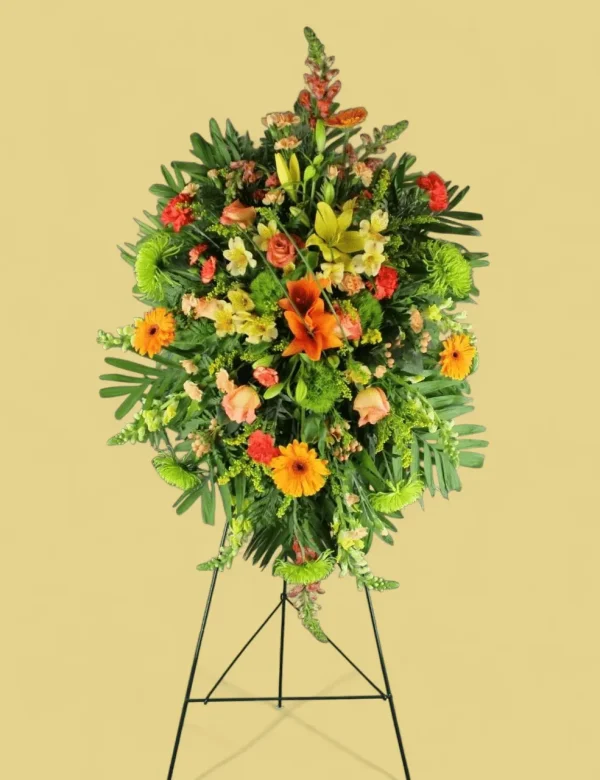 Funeral spray with bright orange lilies, roses, and greenery for memorials.