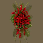 Profile view of red roses and ginger flowers in a heartfelt standing spray.