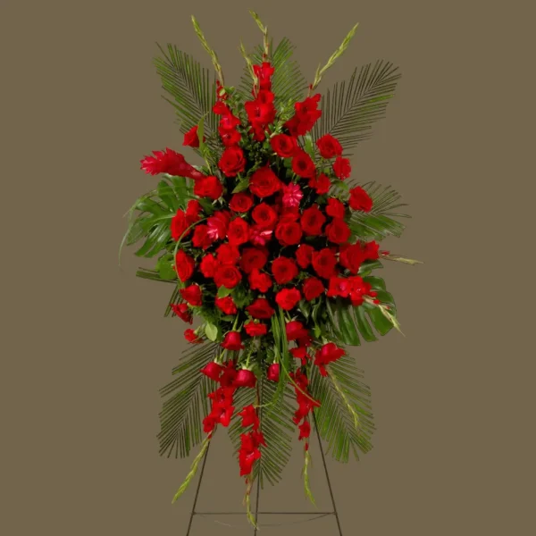 Profile view of red roses and ginger flowers in a heartfelt standing spray.