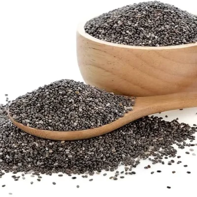 Tiny black and white chia seeds on a wooden spoon, known for their ability to absorb water and form a gel.