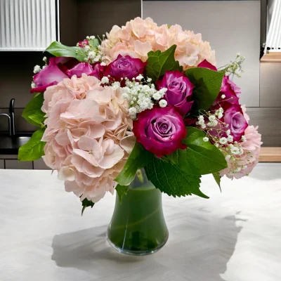 Close-up of fresh purple roses and pink hydrangea arrangement