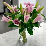 Tabletop arrangement featuring pink lilies in a vase