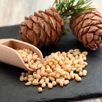 Small, ivory-colored pine nuts scattered on a wooden surface, highlighting their delicate, buttery texture.