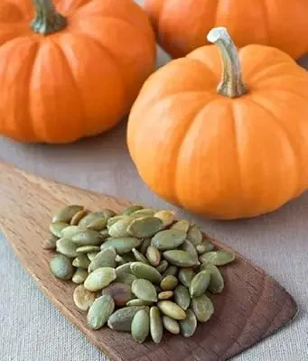 Green, oval pumpkin seeds in a bowl, known for their slightly sweet, nutty taste.