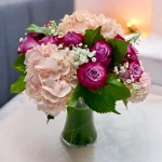 Soft and vibrant purple roses and pink hydrangea in a vase