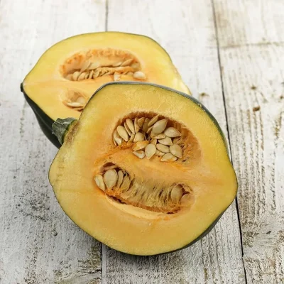 Close-up of white squash seeds embedded in the bright yellow-orange flesh of a sliced squash.