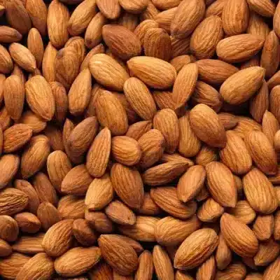 A pile of raw almonds with a light brown, smooth surface, showcasing their slightly elongated shape and crunchy texture.