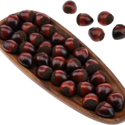 Glossy, reddish-brown chestnuts with a slightly rounded shape, placed on a rustic surface, often associated with roasting.