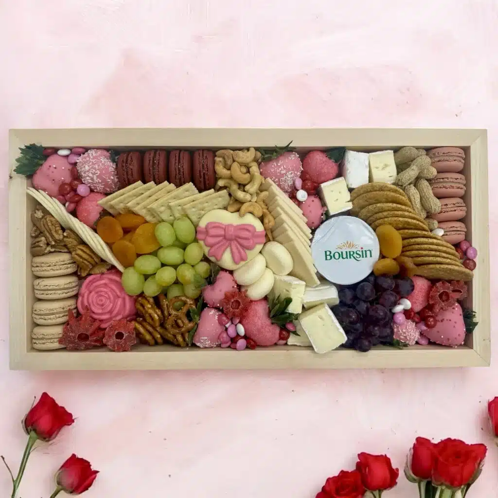 Top view of Valentine’s Day Charcuterie Gift Box with chocolate-covered strawberries, macarons, cheese, and crackers.