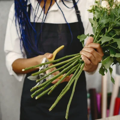 Removing submerged leaves from cut roses to prevent bacterial growth and maintain their freshness.